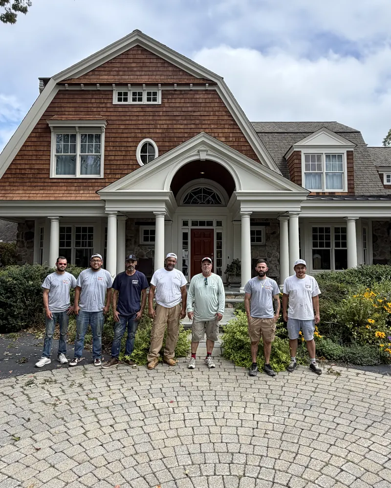Seven Target Painting painters standing in front of a shingle-style home they painted