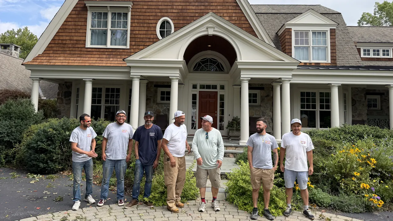 Target Painting painters standing together in front of a shingle-style home they painted