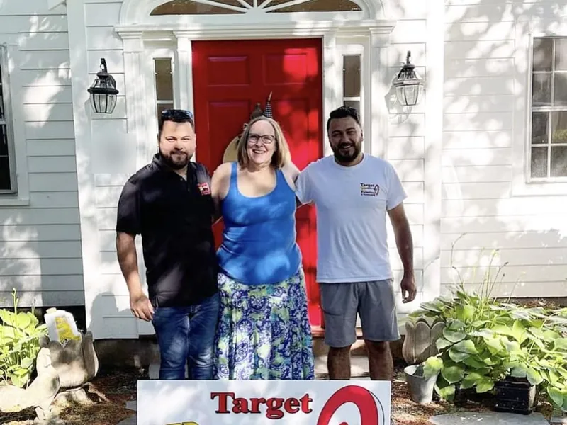Two Target Painting team members with a smiling homeowner at her freshly painted front door