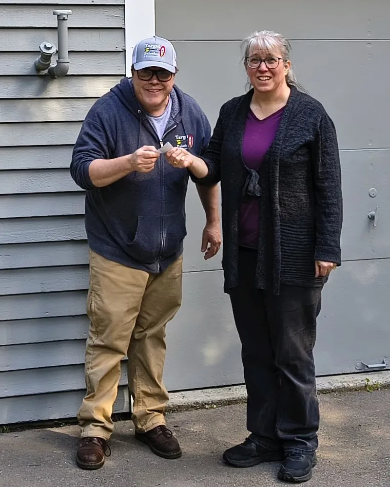 A Target Painting team member handing a key to a smiling woman outside a building