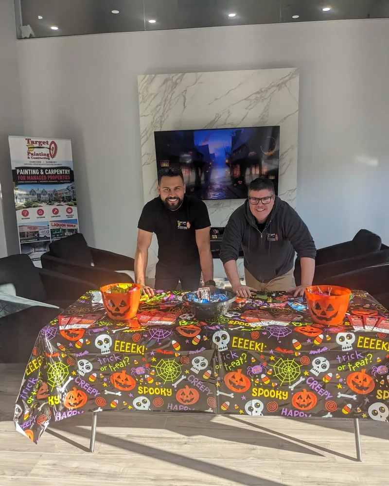 Two Target Painting team members smiling behind a table full of Halloween candy